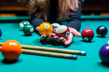 hands of  young slender girl chasing billiard balls on a spacious table in the billiard room.