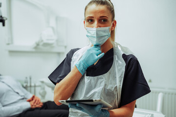 Caucasian female nurse wearing surgical mask and holding digital tablet before assessing male client