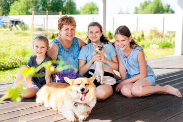 Young grandmother and her three granddaughters with a corgi dog in the backyard of the house