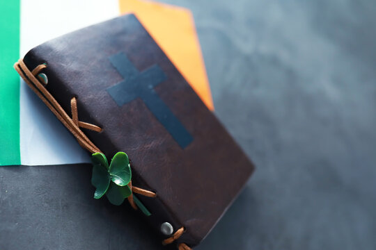 A leather-bound Bible on the table. Religious Christian Irish celebration. Four-leaf clover symbol of good luck.