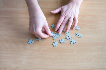 Hands arranging puzzle pieces on table