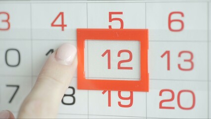 Close-up of a woman's finger moves the date pointer on the calendar