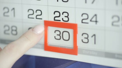 Close-up of a woman's finger moves the date pointer on the calendar