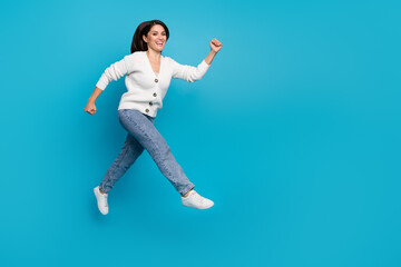 Fototapeta na wymiar Photo of sweet charming woman wear white cardigan running fast jumping high isolated blue color background