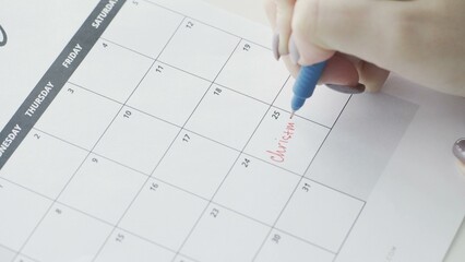 The word Christmas is written in a red pen in a close-up calendar