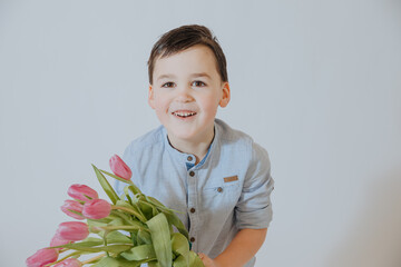 Little boy with flowers. Child gives away tulips. 