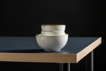 tableware, kitchen utensil and dishes concept - close up of white ceramic bowls on black table