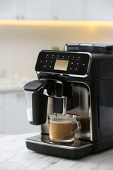 Modern espresso machine and glass cup of coffee with milk on white marble countertop in kitchen