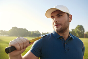 Golfer playing golf on green field at sunny day