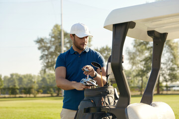 Golfer take putter on golf cart before play golf