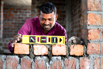 Mason measuring horizontal surface of wall using spirit level at construction site - concept of...