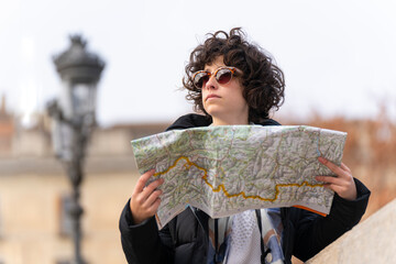 Young tourist woman searches for a place in the city with the help of a map