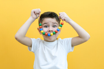 speech therapy, the development of fine motor skills. Toddler boy is stringing beads on a string. happy child