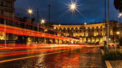 Fototapeta na wymiar Cars light trails in the evening square in Rome right after the rain. Night traffic routes. Motion blur. Cityscape.