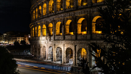 Fototapeta na wymiar Cars light trails near the Coloseum, Rome, Italy. Also Known As Flavian Amphitheatre In Evening Or Night Time. Famous World Landmark