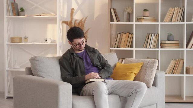 Finished book. Home reading. Domestic leisure. Intelligent man unhappy with favorite bestseller story ending on cozy sofa at living room.