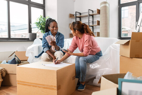 moving, finances and real estate concept - women with money, bills and calculator at new home