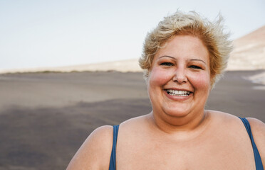 Portrait of curvy woman smiling on camera wearing bikini at the beach - Focus on face