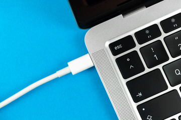 Charging laptop with modern USB Type C port. Laptop low battery concept, technology background,...