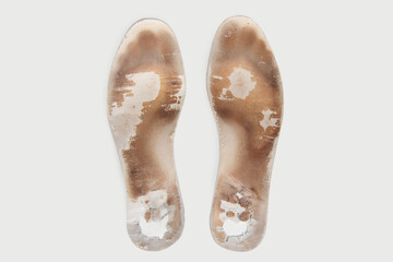 Two old, shabby orthopedic insoles isolated on white background. Dirty leather insoles. Worn out things with holes. Inner soles of shoes. Top view banner close up.