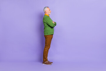 Photo of serious confident man pensioner dressed green pullover arms crossed empty space isolated purple color background