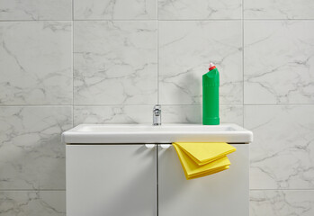 Cleaning kits on the cabinet sink in the bath room, yellow cloth, close up.