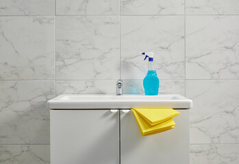 Cleaning kits on the cabinet sink in the bath room, yellow cloth, close up.