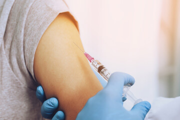 close up doctor holding syringe and using cotton before make injection dose in shoulder of patient in medical mask. Covid-19 or coronavirus vaccine. prevention against flu or virus pandemic concept.