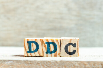 Alphabet letter block in word DDC (Abbreviation of Division of disease control,  Direct digital control, Display Data Channel or Dewey Decimal Classification) on wood background