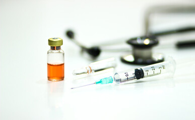 3 ml Plastic Syringe with Needle, Vial and Ampule of Drug,  and Out of Focus of Stethoscope Isolated on the White Background
