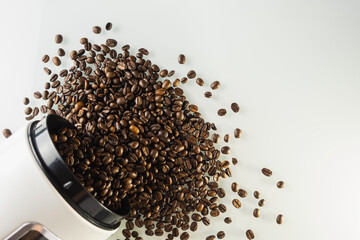 Kaffee Bohnen fallen und verteilen sich aus einer Kaffee Dose auf eine helle Oberfläche nah