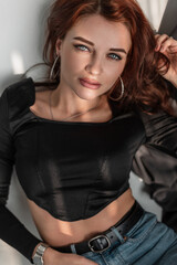 Pretty young woman with beautiful blue eyes in fashion black t-shirt and blue jeans lies in the room with sunlight.
