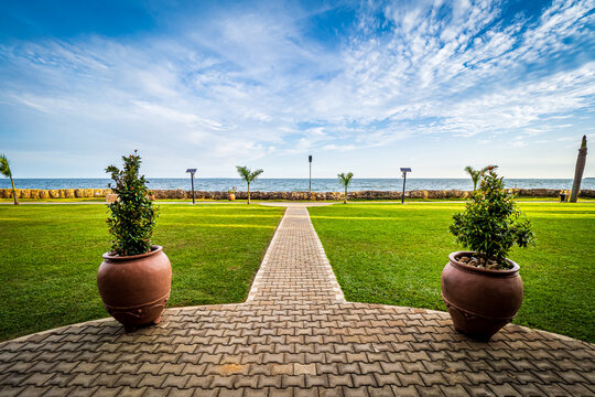 View of the walkway in a park on the shore of Lake Victoria in Entebbe, Uganda, with two potted plants in the foreground