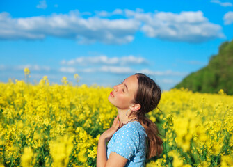 Naklejka na ściany i meble Beautiful teen girl is smiling with yellow flowers in summer field