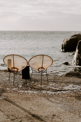 Relaxing scene at a holiday lounge deck by the sea overlooking blue waves and ocean, sun reflecting in water, blue sky and rocks in the background