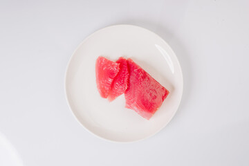 a piece of fresh tuna on a white plate on a white background
