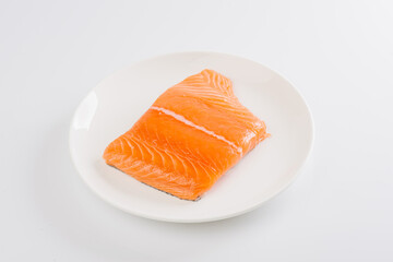 raw salmon fillet on a white plate on a white background