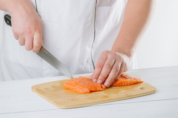 the chef cuts salmon on a wooden board, on a white background