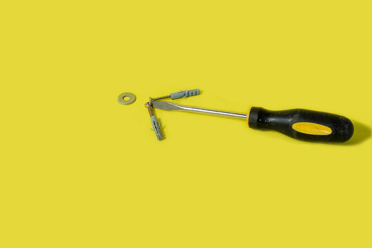 herramientas de trabajo el&eacute;ctrico, destornillador, llave, tornillos sobre una mesa de color amarilla