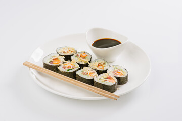 Sushi with chopsticks on a white plate. Sushi roll japanese food in restaurant isolated on white background. Fresh hosomaki pieces with rice and nori.
