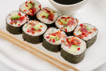 Sushi with chopsticks on a white plate. Sushi roll japanese food in restaurant isolated on white background. Fresh hosomaki pieces with rice and nori.