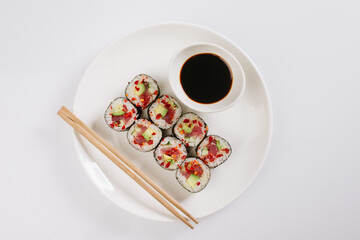 Fototapeta na wymiar Sushi with chopsticks on a white plate. Sushi roll japanese food in restaurant isolated on white background. Fresh hosomaki pieces with rice and nori.
