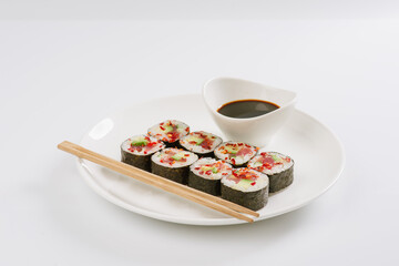 Sushi with chopsticks on a white plate. Sushi roll japanese food in restaurant isolated on white background. Fresh hosomaki pieces with rice and nori.