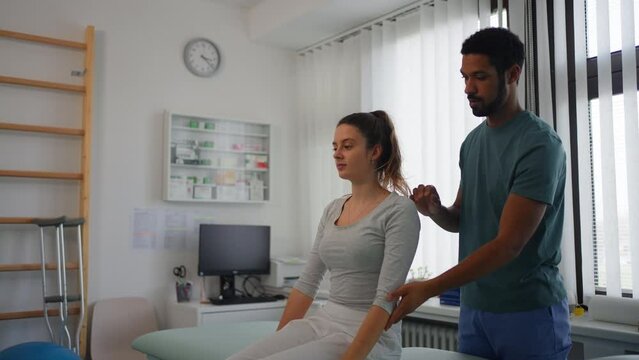 Young male physiotherapist exercising with young woman patient in a physic room