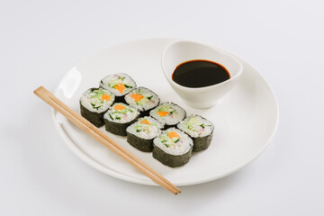 Sushi with chopsticks on a white plate. Sushi roll japanese food in restaurant isolated on white background. Fresh hosomaki pieces with rice and nori.