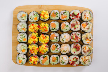 Maki Sushi Rolls set on wooden board. Japanese traditional Cuisine. White background.
