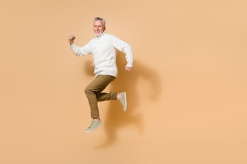Fototapeta na wymiar Full length body size view of attractive cheerful man jumping running fast isolated on beige pastel color background