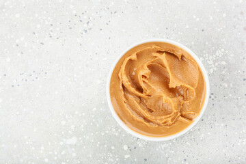 smooth peanut butter in bowl on gray background