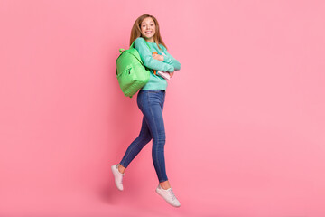 Photo of excited girl wear turquoise sweater jumping walking hugging school supplies isolated pink color background