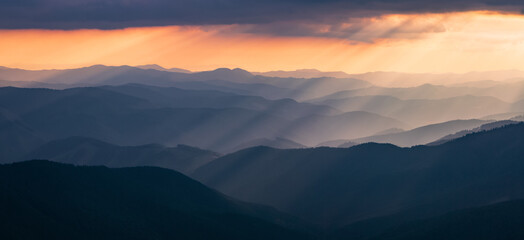 Panorama with amazing sunrise. Landscape of high mountains and forests. The sun rays are shining through the fog. The play of light and shadows. Location Carpathians, Ukraine, Europe. Natural scenery.